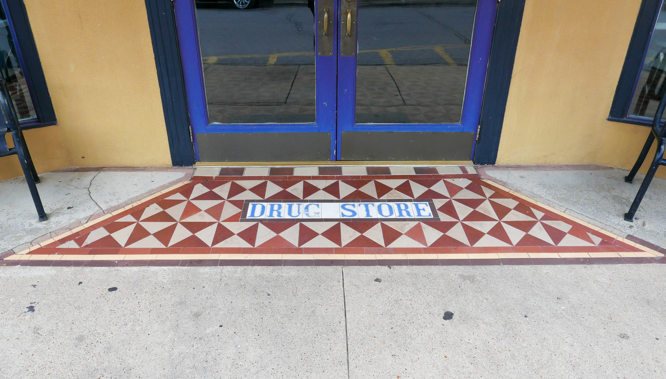 Independent community pharmacy storefront with an open front door.